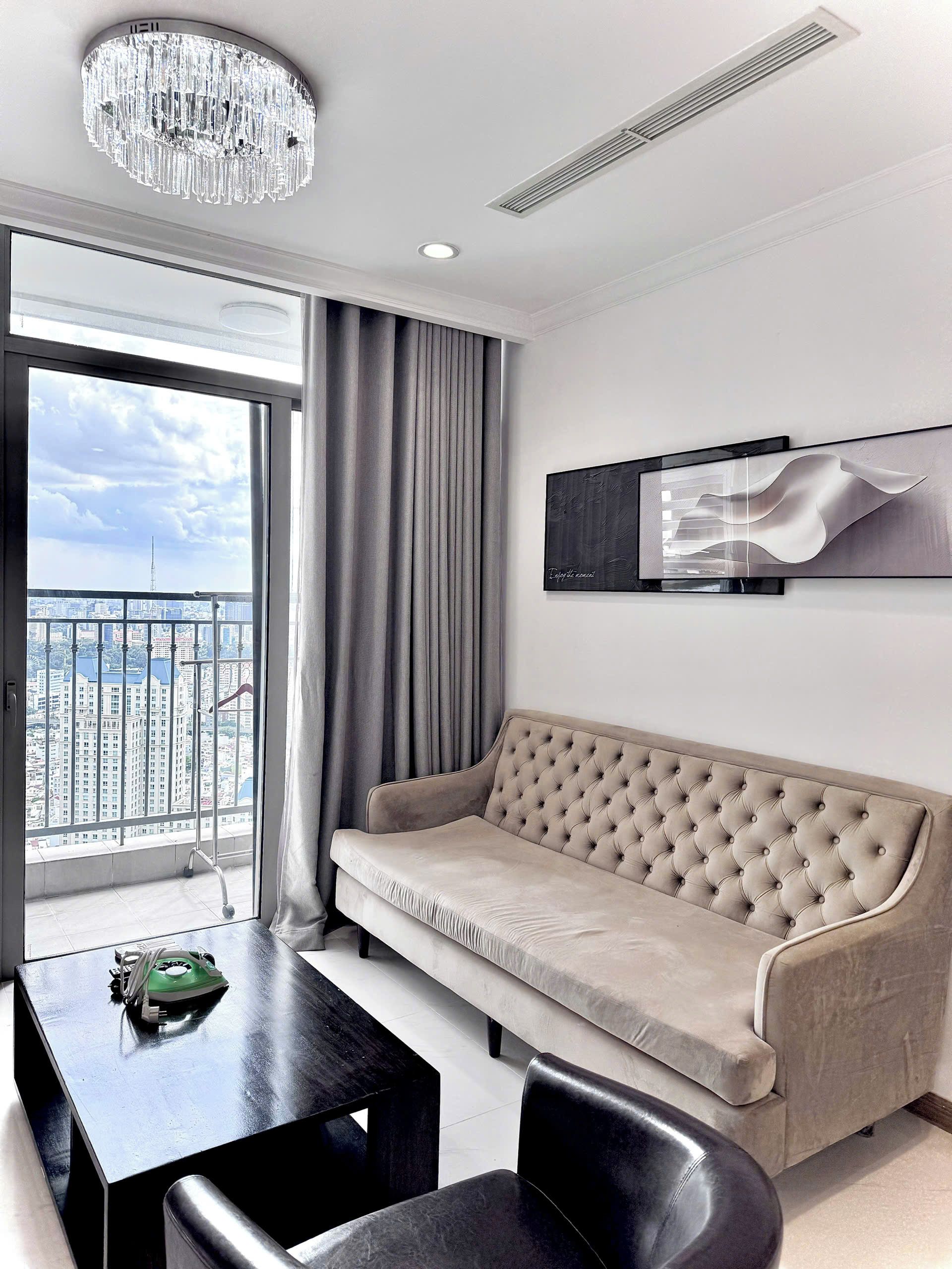 Un salon moderne avec un canapé, une table à manger et des chaises. Une grande fenêtre offre une vue sur le paysage urbain.