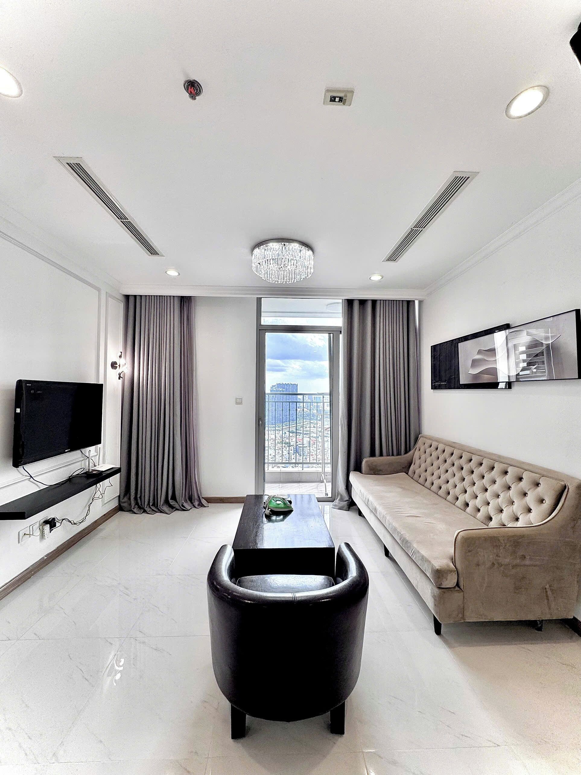 Ein modernes Wohnzimmer mit Fernseher, Sofa, Couchtisch und Blick durch eine Balkontür.