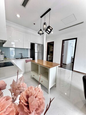 Una cocina moderna con armarios blancos, un refrigerador de acero inoxidable y una encimera de madera.