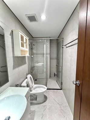 Un baño moderno con ducha acristalada, inodoro y lavamanos.