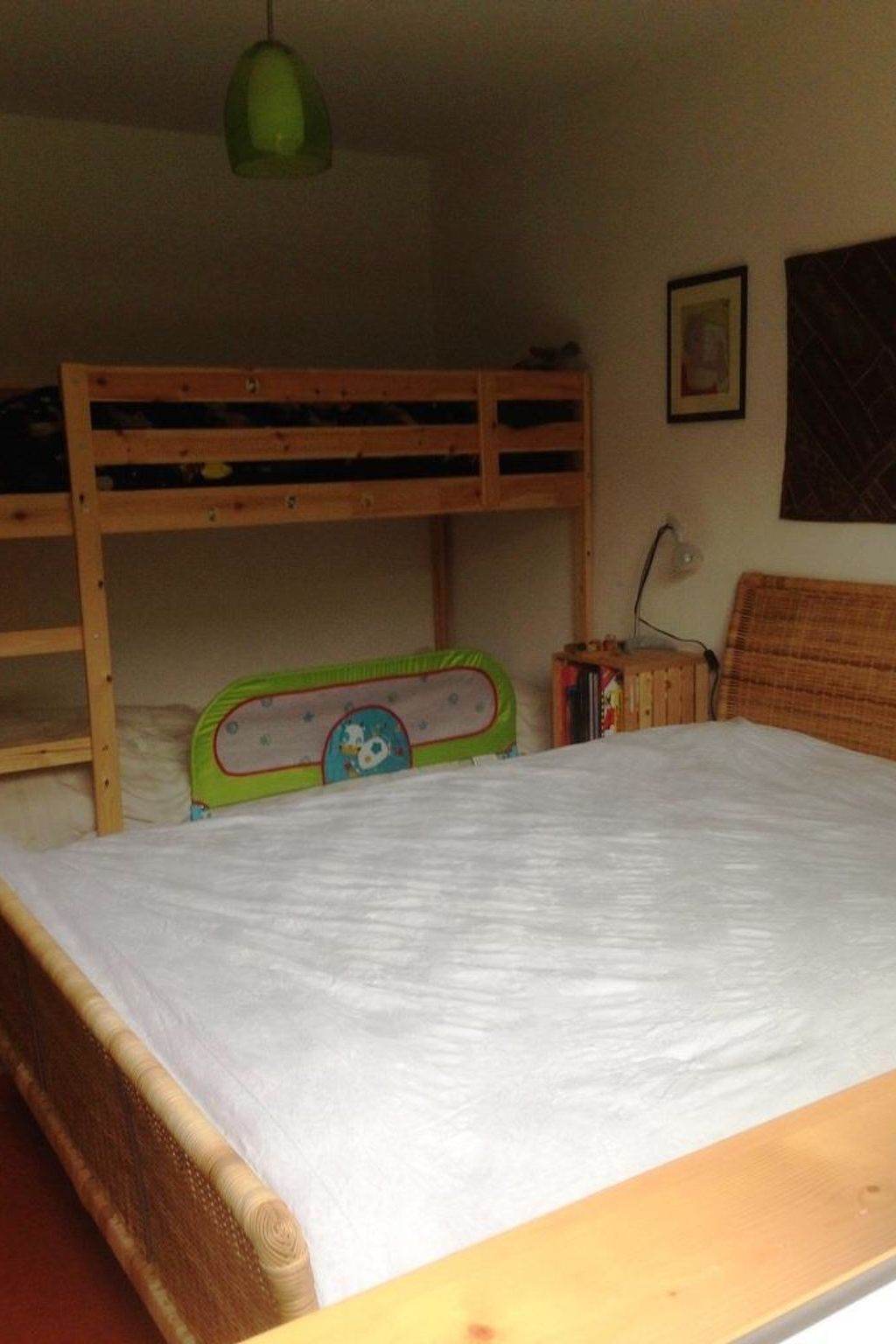 Un lit superposé avec une lampe suspendue verte au-dessus.