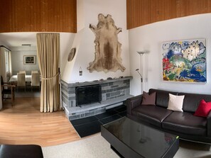 Ein modernes Wohnzimmer mit Kamin aus Stein, einer Ledersofa und einem großen abstrakten Gemälde.