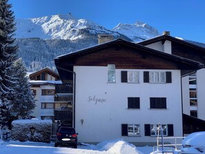 Ein zweistöckiges Gebäude mit einem Skigebiet im Hintergrund.