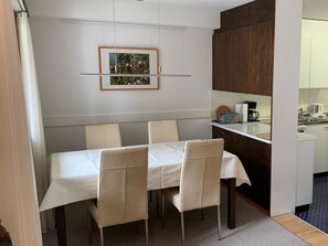 A dining area with a table and chairs, a kitchen area with cabinets and appliances, and a framed picture on the wall. - Sul Prau 9 Appartement/Fewo, Dusche oder Bad, WC 3½-Zimmerwohnung by Interhome (Klosters)