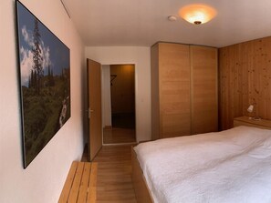 A bedroom with a bed, wooden wardrobe, and a painting of a landscape. - Sul Prau 9 Appartement/Fewo, Dusche oder Bad, WC 3½-Zimmerwohnung by Interhome (Klosters)