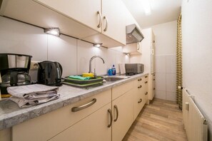 Eine kompakte Küche mit Arbeitsplatte, Spüle, Herd und Mikrowelle.