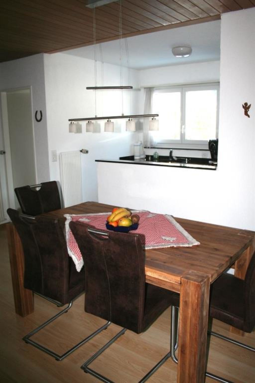 Un coin repas avec une table en bois, des chaises et un panier de fruits.