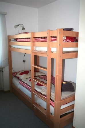 A bunk bed with a desk and lamp, in a room with white walls and a window. - Chesa Grischa 12 Appartement/Fewo, Dusche oder Bad, WC 3½-Zimmerwohnung by Interhome (Davos)