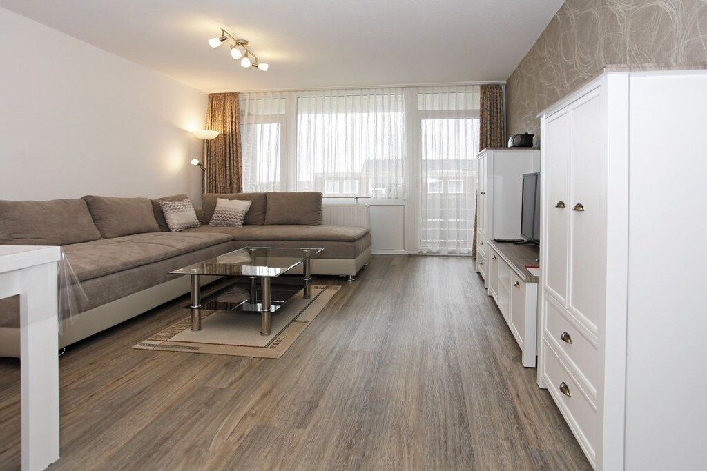 A modern living room with a sectional sofa, a glass coffee table, and a white cabinet.