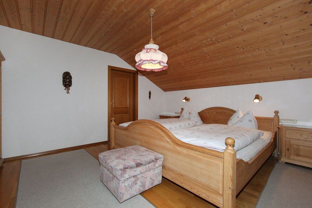 Une chambre avec un plafond en bois, un lit avec une tête de lit, une table de chevet et une lampe suspendue.