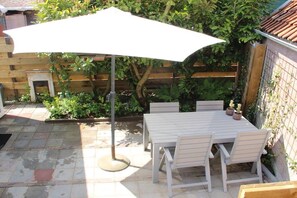 A patio with a table and chairs, an umbrella, and a wooden fence. - Holiday apartment with 1 bedroom (Oostkapelle)