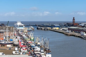 Ein Hafen mit vertäuten Booten an den Kais, einem Kran und Fabrikgebäuden im Hintergrund.
