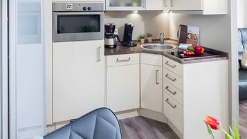 Eine moderne Küche mit weißen Schränken, einem eingebauten Backofen, einer Kaffeemaschine und einem Spülbecken.