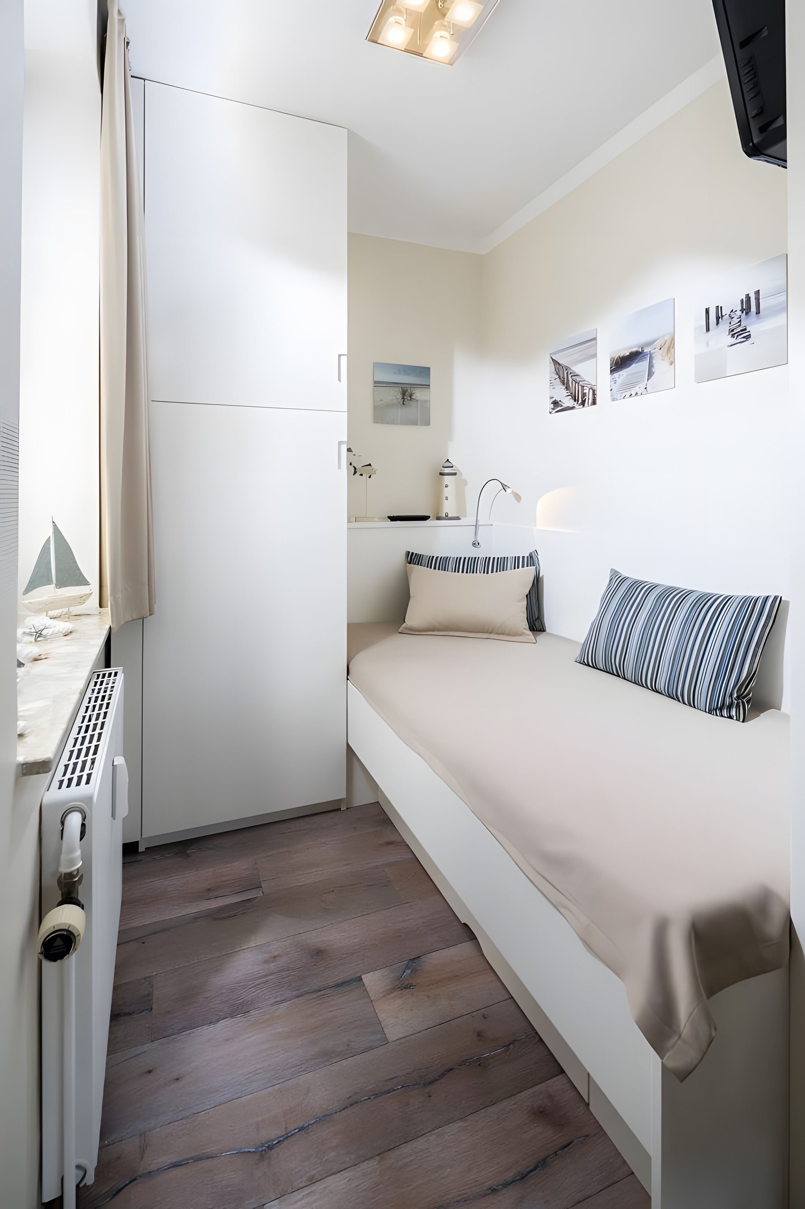 Ein gemütlicher Raum mit Bett, kleinem Tisch, Heizkörper und einem Fenster mit Vorhängen.