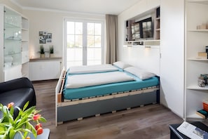 Ein modernes Schlafzimmer mit Bett, Schreibtisch, Stuhl und Fernseher.