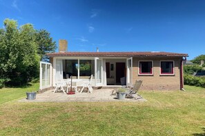 A single-story house with a patio area, a covered outdoor seating space, and a brick exterior. - Previnaireweg 46 & 48 (Callantsoog)