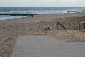 A beach with a wooden walkway and a few people in the distance. - Holiday apartment with 1 bedroom (Callantsoog)