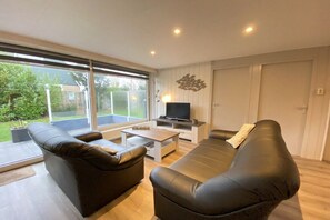 A modern living room with a sofa, a coffee table, and a TV. - Bungalow with 1 bedroom (Callantsoog)