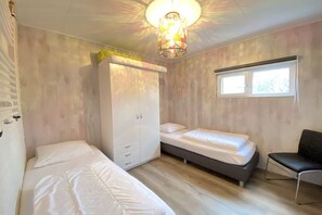 A room with two beds, a wardrobe, a chair, and a window. - Bungalow with 1 bedroom (Callantsoog)