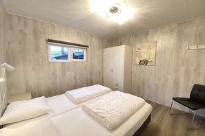 A bedroom with a bed, a wardrobe, a chair, and a window. - Bungalow with 1 bedroom (Callantsoog)
