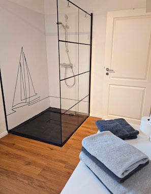 A room with a glass partition, a wooden floor, and a white door.
