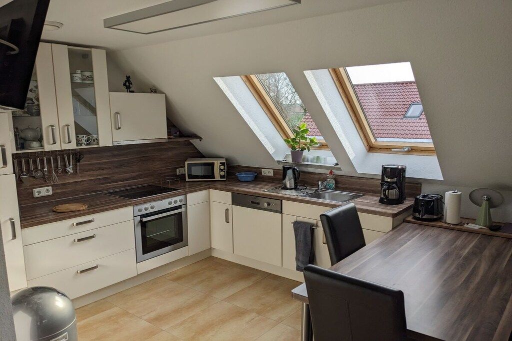 Een moderne keuken met een eethoek, dakramen en uitzicht op het omliggende landschap.
