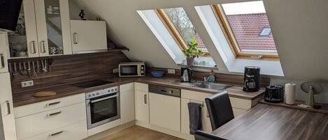 Een moderne keuken met een eethoek, dakramen en uitzicht op het omliggende landschap.