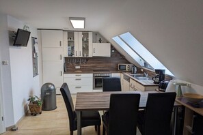 Eine kompakte Küche mit Essbereich, einem Mülleimer und einer kleinen Pflanze.