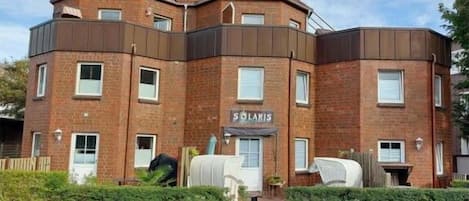 Un immeuble à plusieurs étages avec une façade en briques, une enseigne indiquant « SOLARIS » et une zone d’entrée pavée.