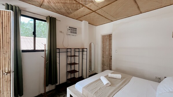A room with a bed, a window with curtains, a wardrobe, and a mirror.