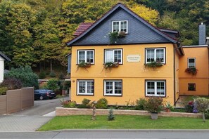 Ein zweistöckiges Gebäude mit gelber Fassade, vielen Fenstern und einem dunklen Dach.