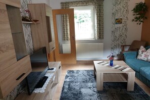 A furnished living room with a sofa, coffee table, and a television. - Schiel Country House (Rohrbach)