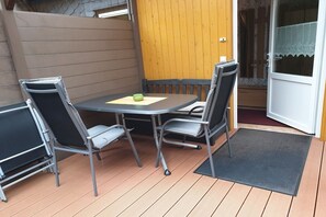 An outdoor patio with a table and four chairs, a doormat, and a wooden fence. - Schiel Country House (Rohrbach)