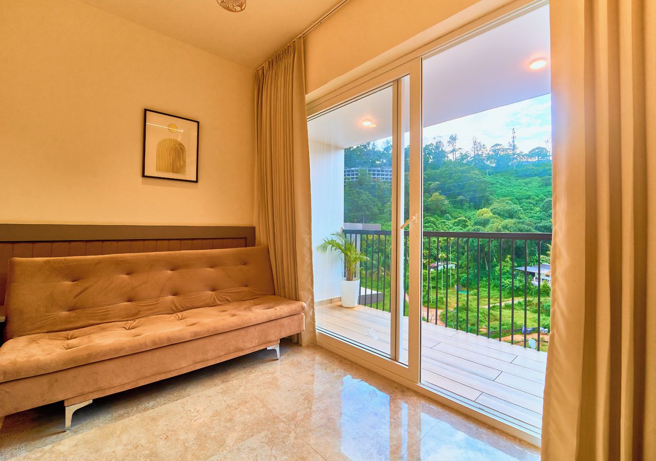Quarto com sofá, quadro na parede e varanda com vista para vegetação.