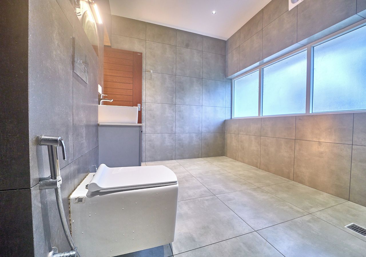 A modern bathroom with a shower, a toilet, and a sink.