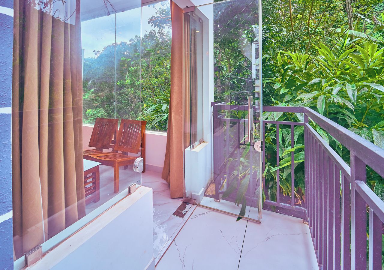 Un balcón con vistas a exuberante vegetación y una silla de madera.