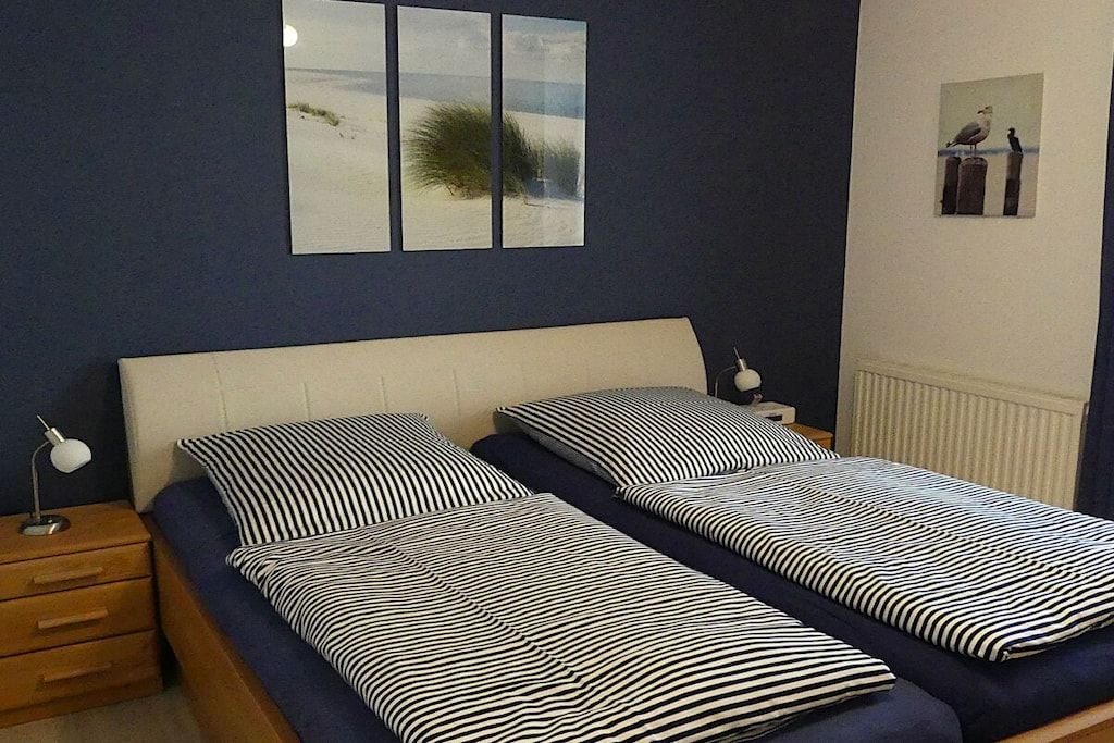 Quarto com duas camas de solteiro, mesa de cabeceira com abajur e um quadro na parede.