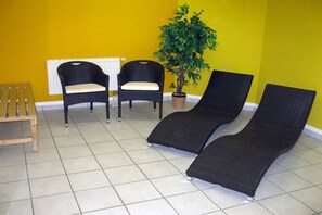A room with two wicker lounge chairs, a wooden bench, and a potted plant. - BOOTY 55, "Am Stadtwald", Apartment 9 (Kühlungsborn)
