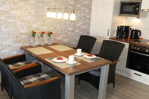 A dining area with a brick wall, a wooden table, and four chairs. - BOOTY 55, "Am Stadtwald", Apartment 9 (Kühlungsborn)