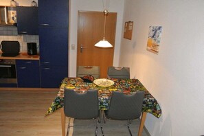 Ein Essbereich mit einem Tisch, der mit einer bunten Tischdecke bedeckt ist, zwei Stühlen und einer hängenden Leuchte.
