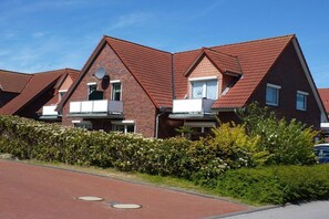 Une rangée de maisons modernes en briques, dotées de toits à deux versants et d’antennes paraboliques.