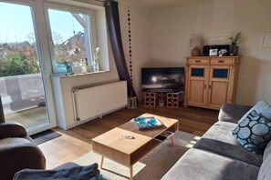 A living room with a sofa, a coffee table, a TV, and a cabinet. - Holiday apartment with 1 bedroom (Hooksiel)