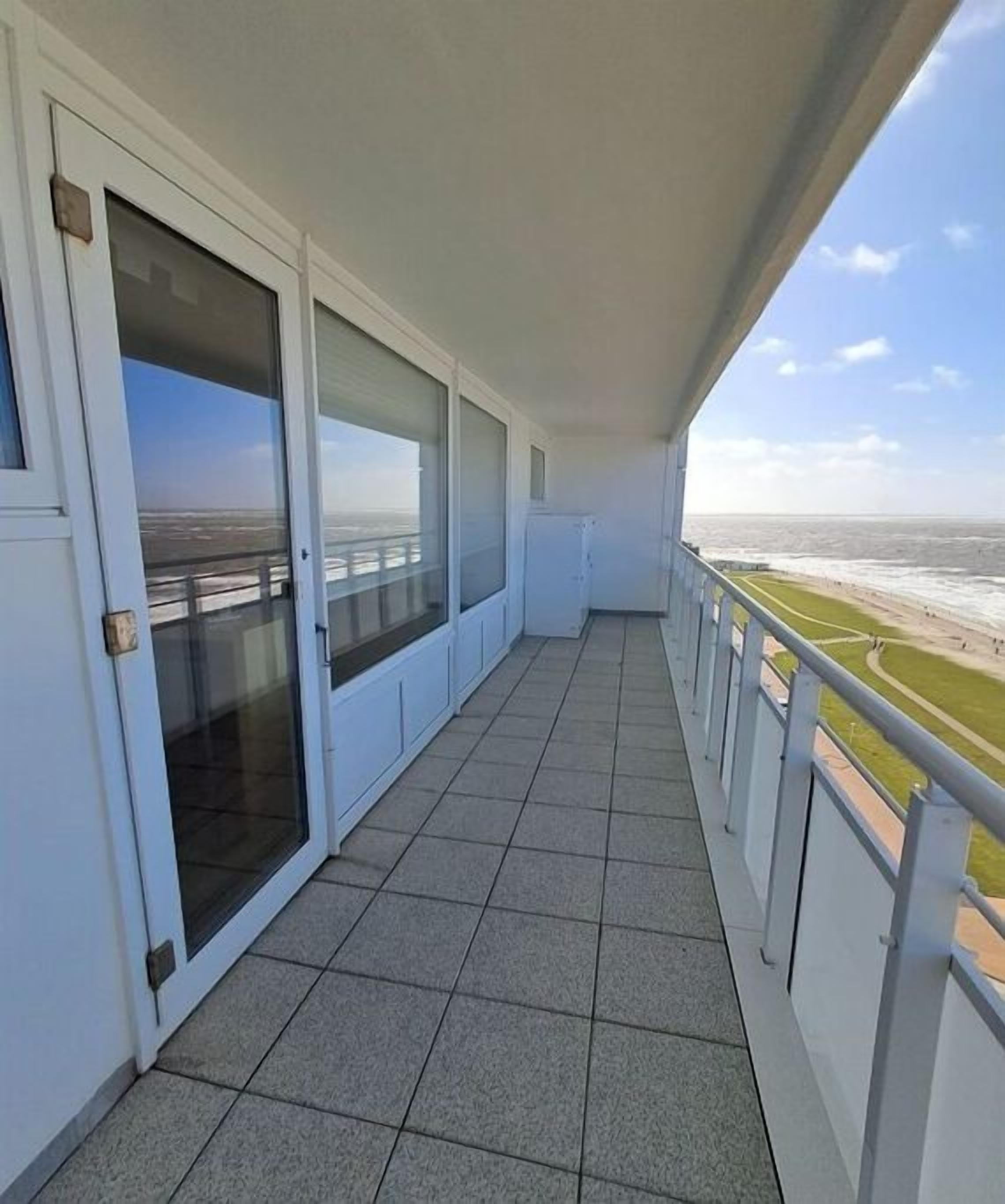 A balcony with a view of the sea and a bridge.