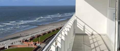 A balcony with a view of the beach and ocean.