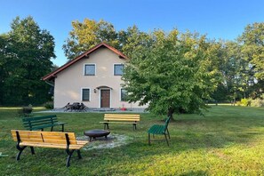 Ein Haus mit rotem Dach, einer Haustür und einer kleinen Veranda mit Gartenmöbeln.