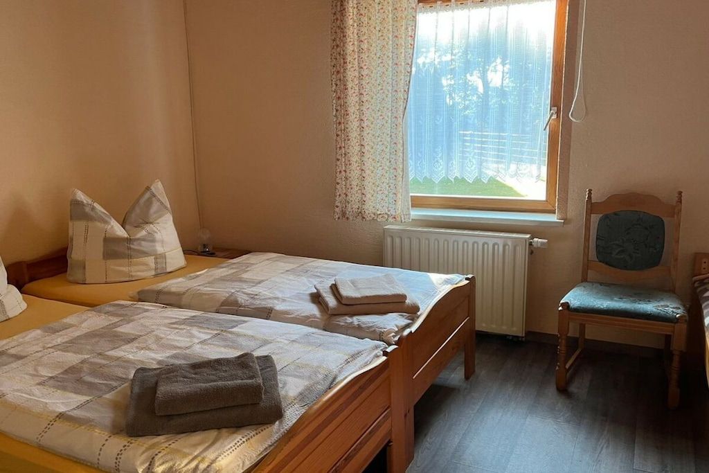 Ein Schlafzimmer mit zwei Betten, einem Sessel und einem Fenster mit Vorhängen.