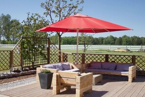 A wooden deck with a red umbrella, wooden benches, and a lattice fence. - MAJA The Spree Garden (Cottbus)