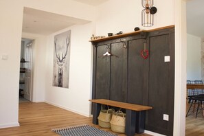 A hallway with a wooden bench, a coat rack with hangers, and a large deer painting on the wall. - MAJA The Spree Garden (Cottbus)