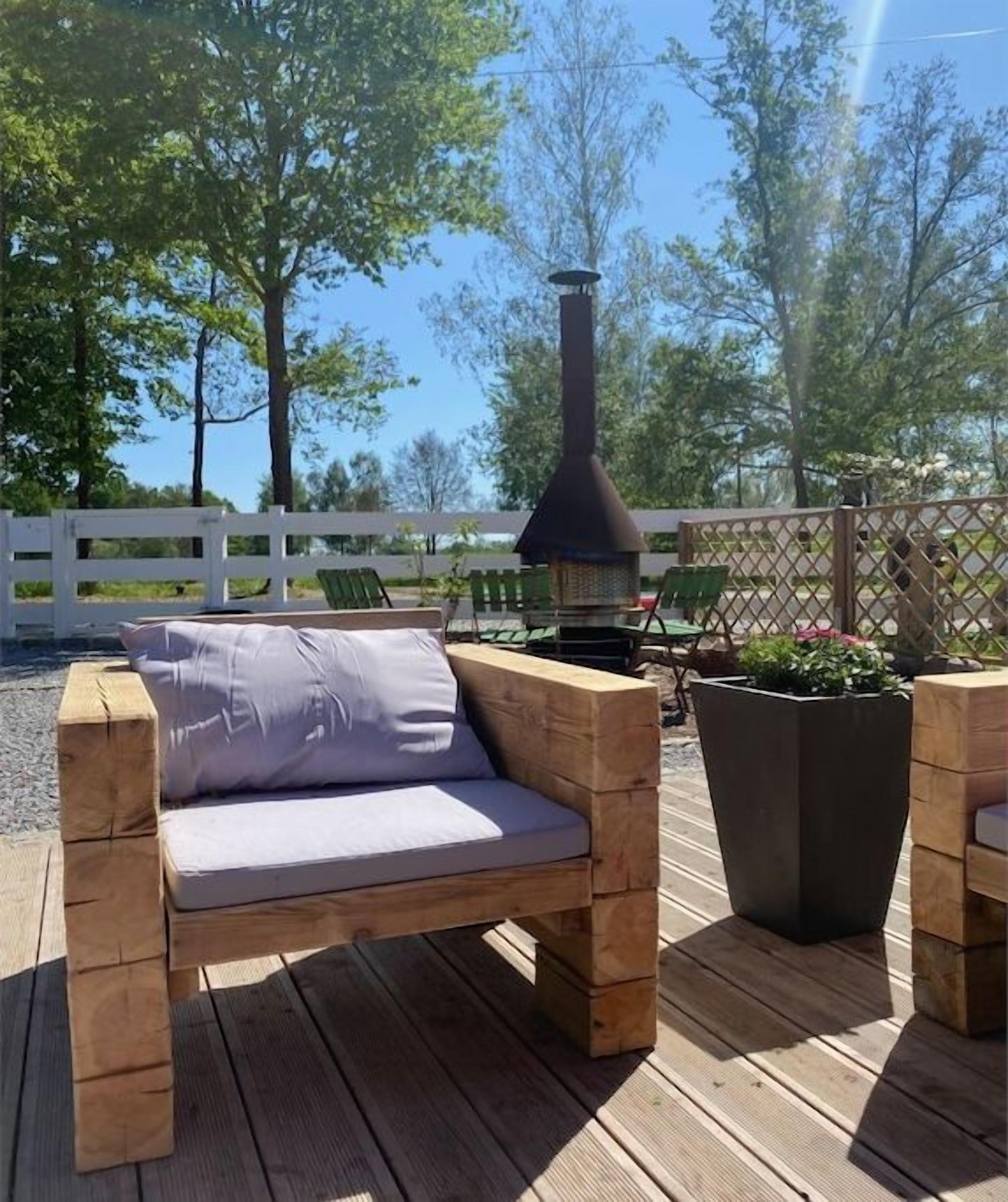 A wooden deck with a cushioned bench and a planter.