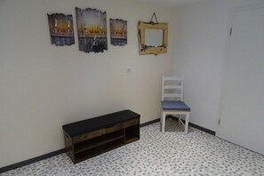 A room with a bench, a chair, and three wall-mounted paintings. - Holiday apartment with 2 bedrooms (Friedrichskoog)